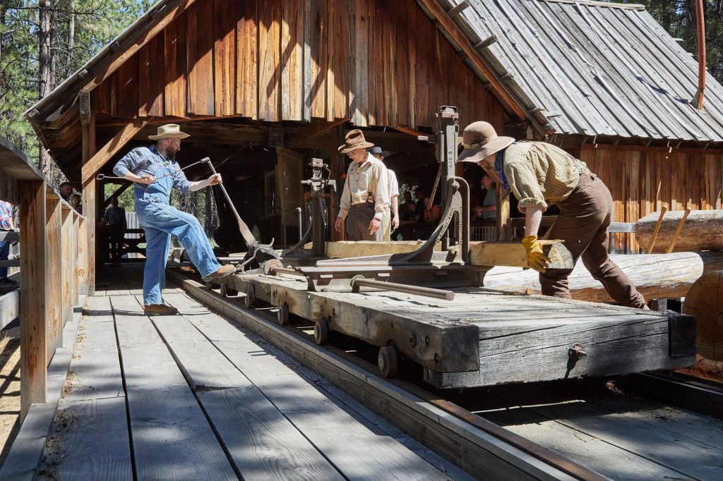 sawmill being operated by three men in turn-of-the-century clothing