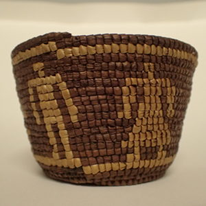 small brown woven basket with lighter colored bands around the top and bottom and two stick figures, one representing a man and one representing a woman