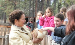 Linda with kids petting a chicken